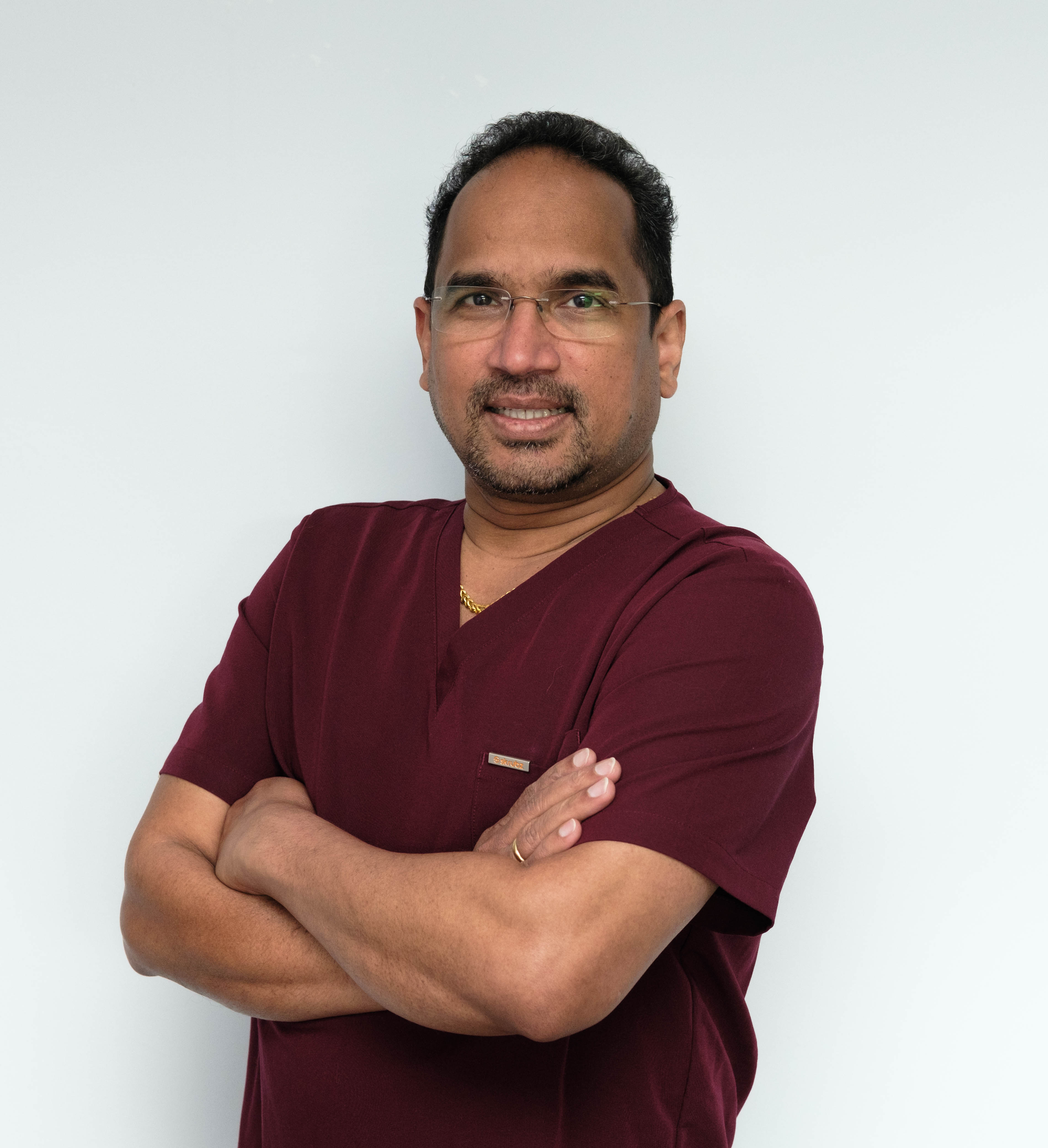 Portrait of Dr Reddy in clinical scrubs, arms crossed